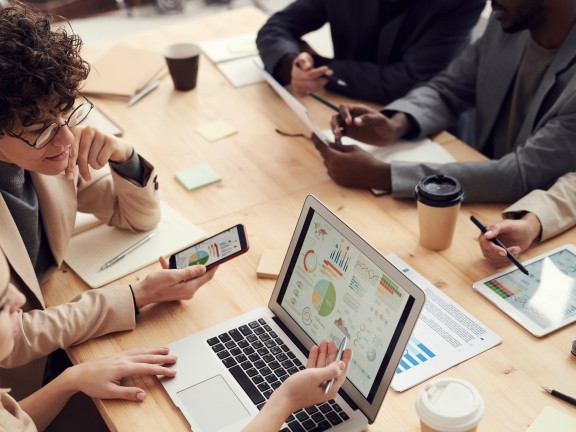 People gathered around a table looking at a laptop