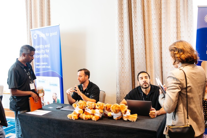 Attendees talking to sponsors at a table with logo bears