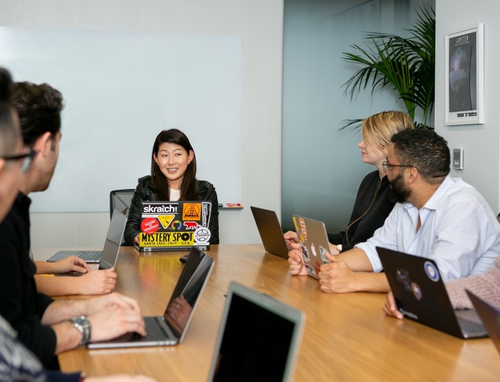 People at a meeting table all with laptops in business casual attire.