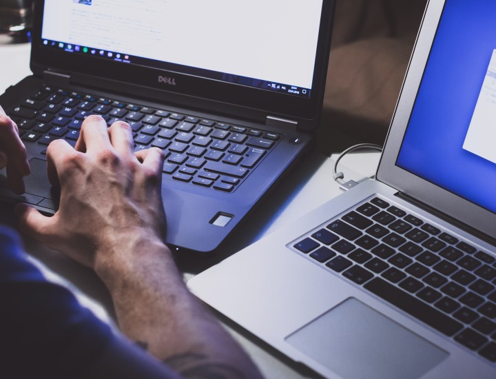 two laptops, one man typing.