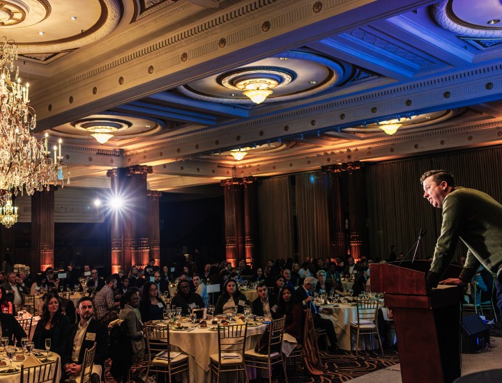 Man talking to crowd of luncheon attendees from the stage