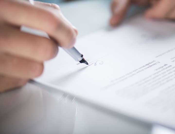 a hand holding a pen signing a paper