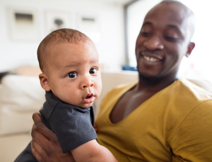 A father holding his baby smiling